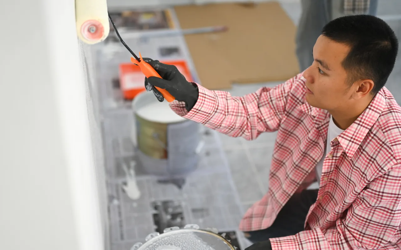 A painter rolling an interior wall — the fastest surface on the production rate table, at roughly twice the pace of a door.