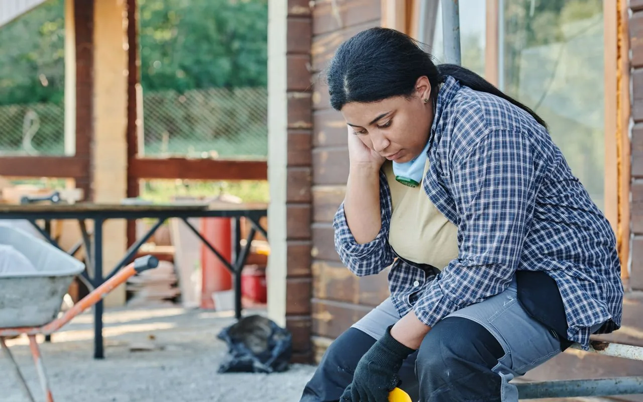 A worker sitting head in hand at the end of a finished job, where the money went missing before the invoice was raised.