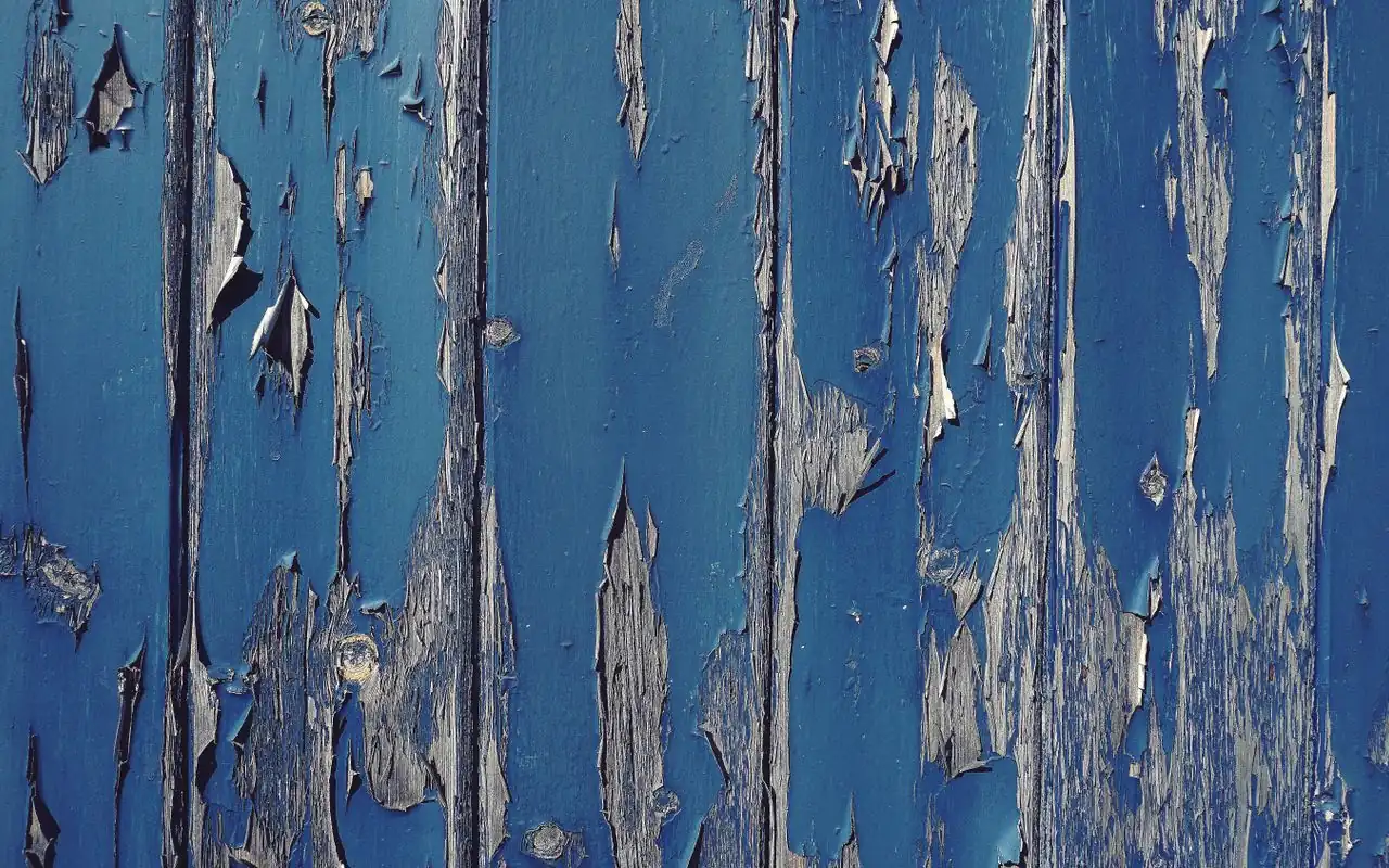Blue painted timber boards with the paint cracked and lifting away — the failure a homeowner can spot without a ladder.