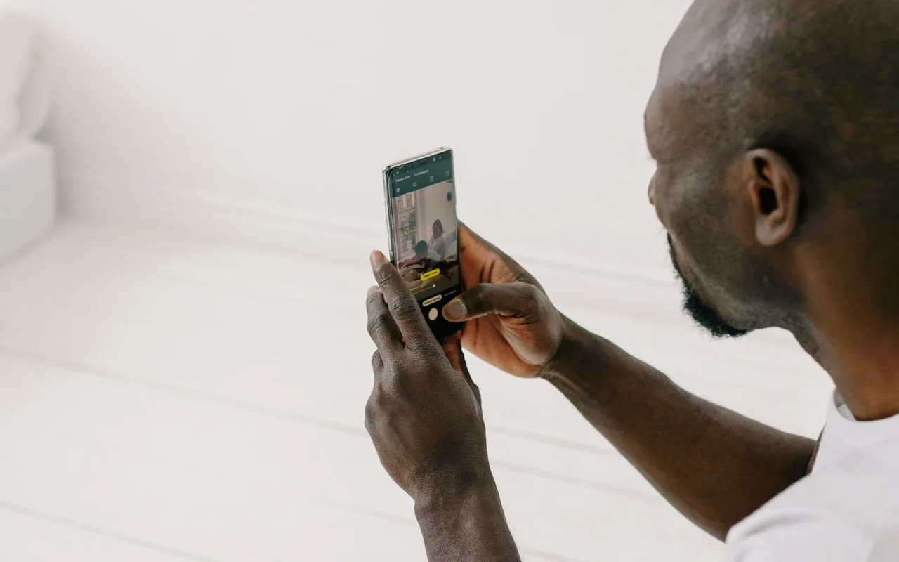 A painter photographing a wall on a phone — photo analysis assists the estimate, it does not measure the wall.