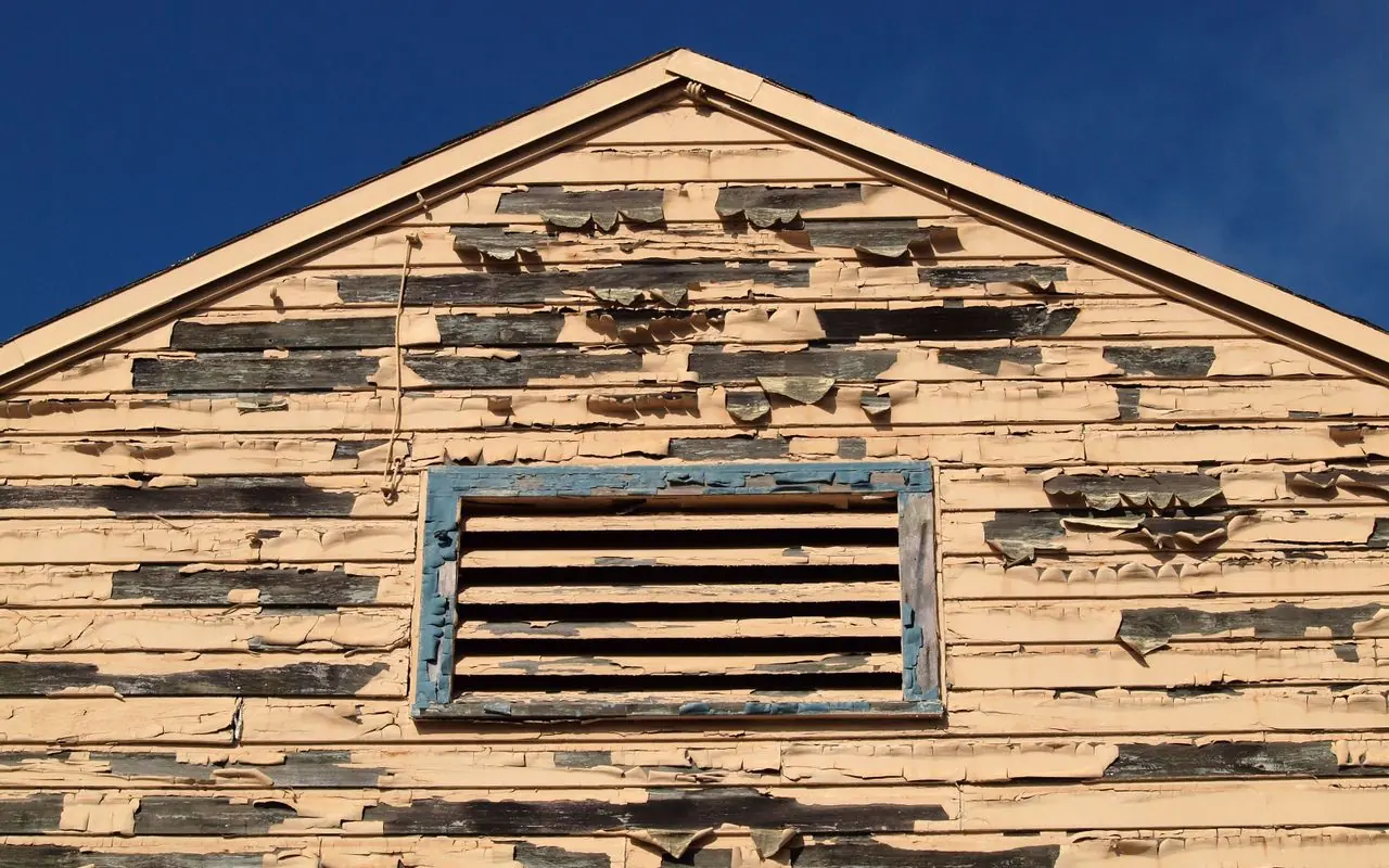 A weatherboard gable stripped bare by the sun, the prep load a 10% allowance never covers.