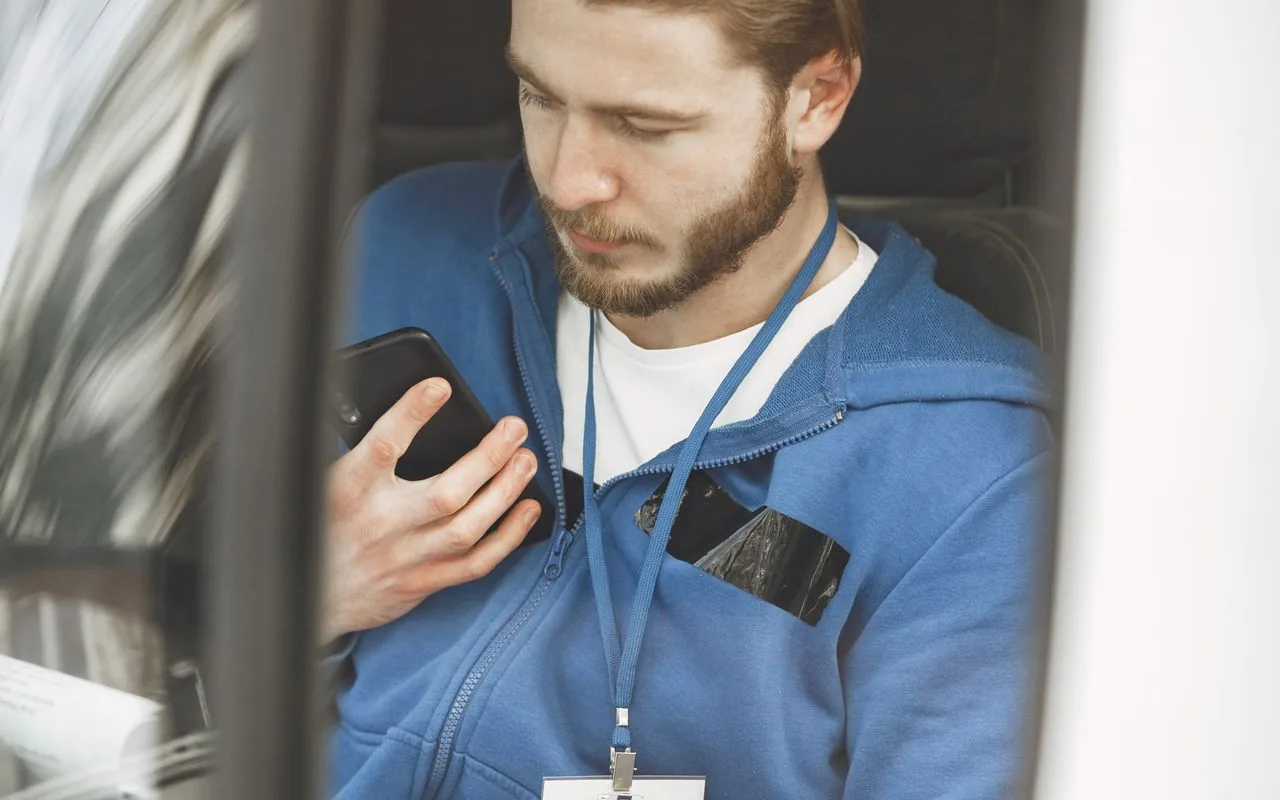 A tradesperson working on a phone in the vehicle straight after a site visit, while the job is still warm.