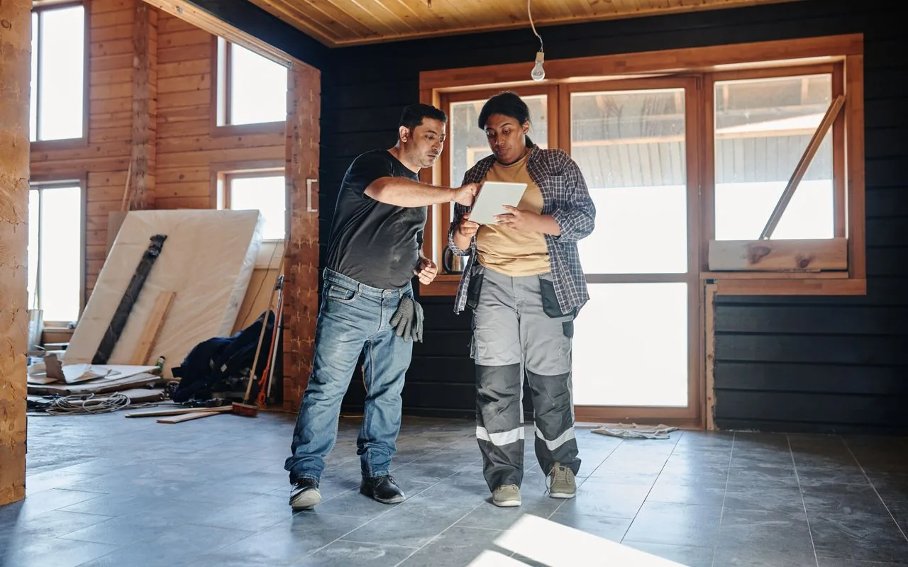 An experienced tradesperson walking a newer estimator through a job on site, week one of a structured handover.